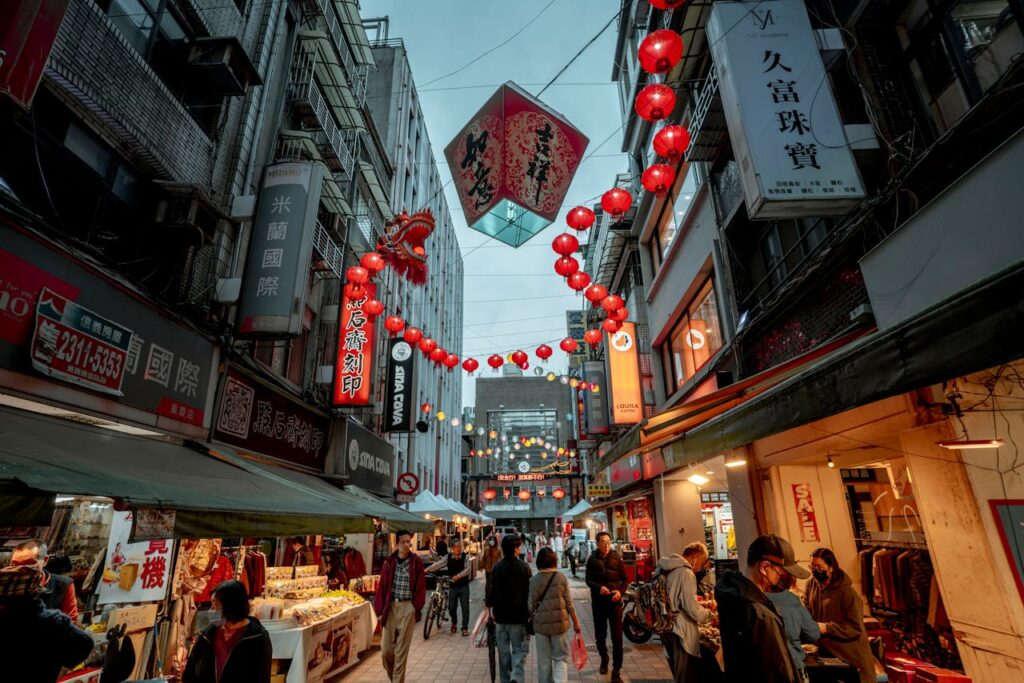 A bustling city street with illuminated lanterns and people at a night market.